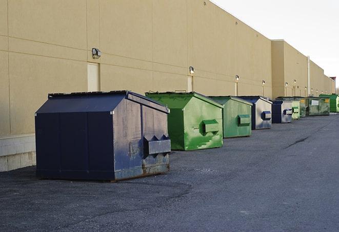 a construction worker unloading debris into a blue dumpster in Apollo Beach